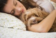 woman sleeping with her small dog in bed