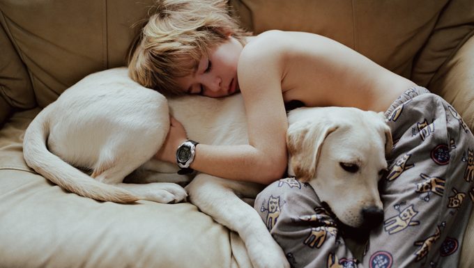 kid hugging dog on couch