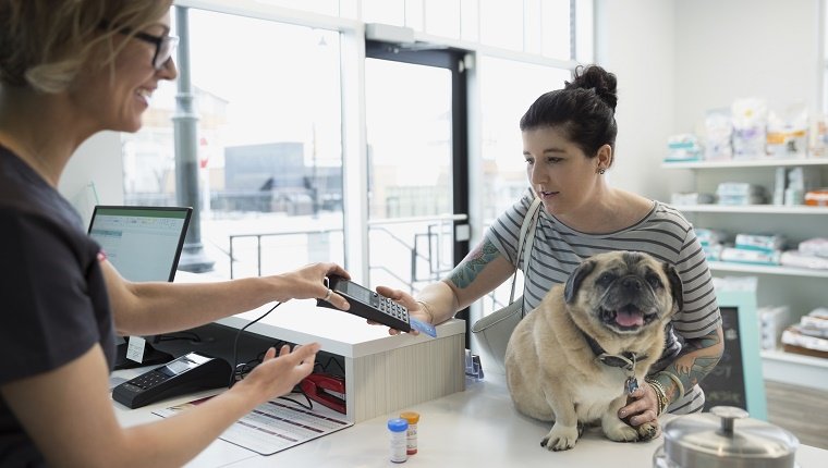 Woman with dog using credit card machine veterinarian