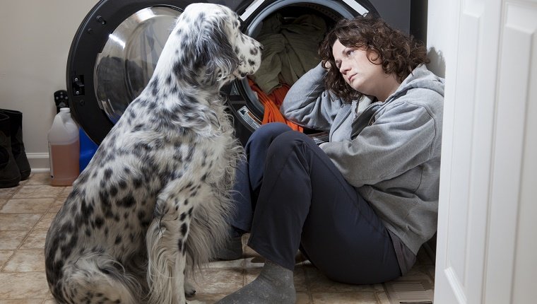 Woman crying on the floor while her dog tries to comfort her