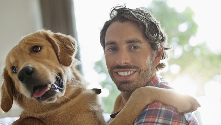 Smiling man petting dog indoors