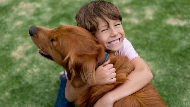 Portrait of a happy boy outdoors hugging a beautiful dog - lifestyle concepts