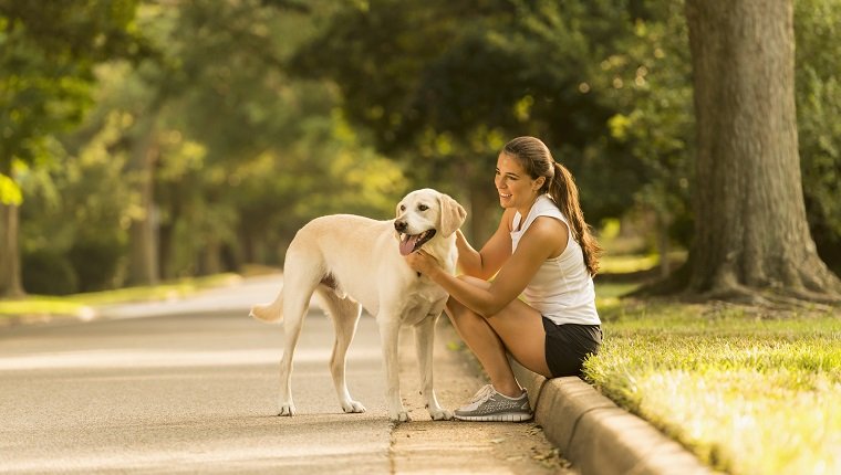 Caucasian woman petting dog on neighborhood street