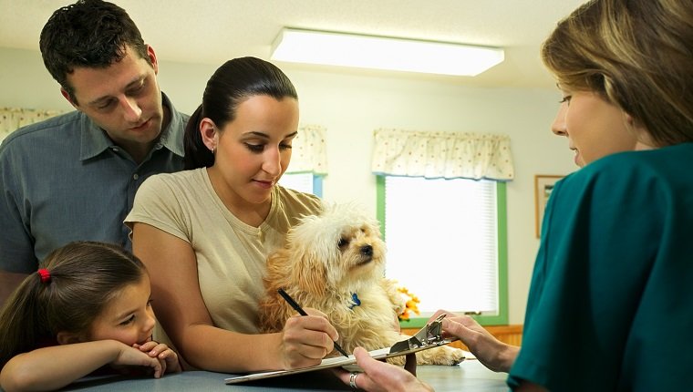 Family with dog filling out paperwork at vet clinic