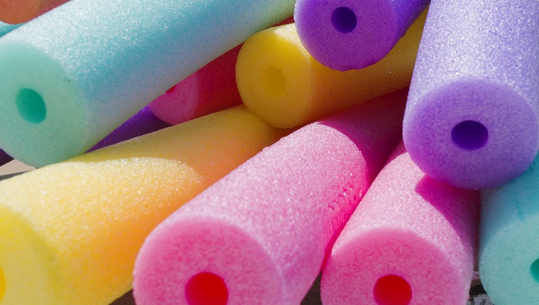 Colorful foam noodles stacked by swimming pool.