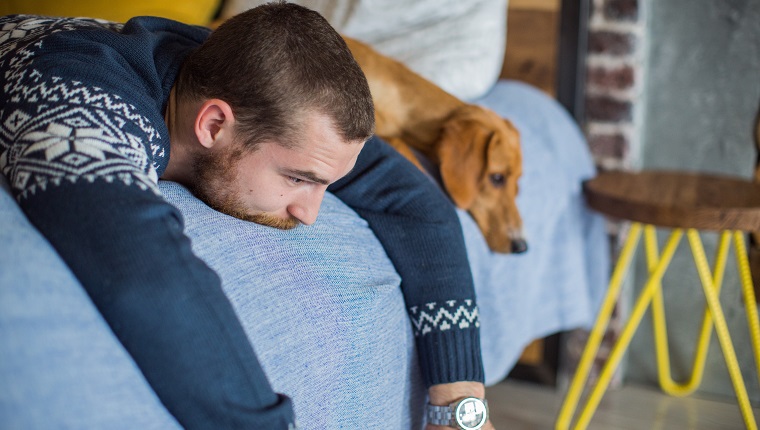 Young man laying on the bed with his dog.