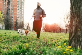 Man jogging with his pet, Staffordshire bull terrier. He is jogging in his neighborhood, in local park.