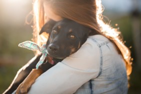 Girl hugging her cute black mutt dog