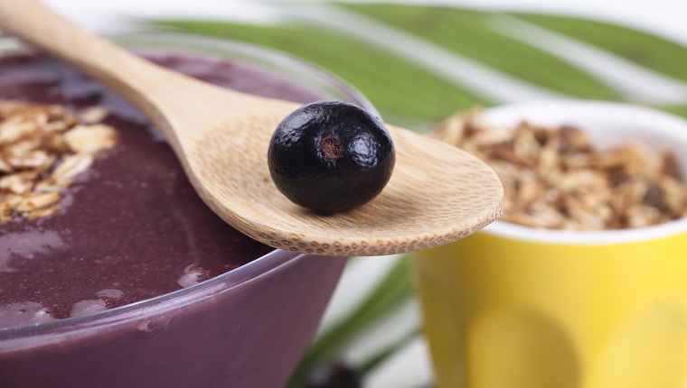 Studio shot of açai fruit on white background with the natural leaves of palm tree.