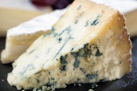 A selection of cheeses and grapes arranged on a slate cheese board.