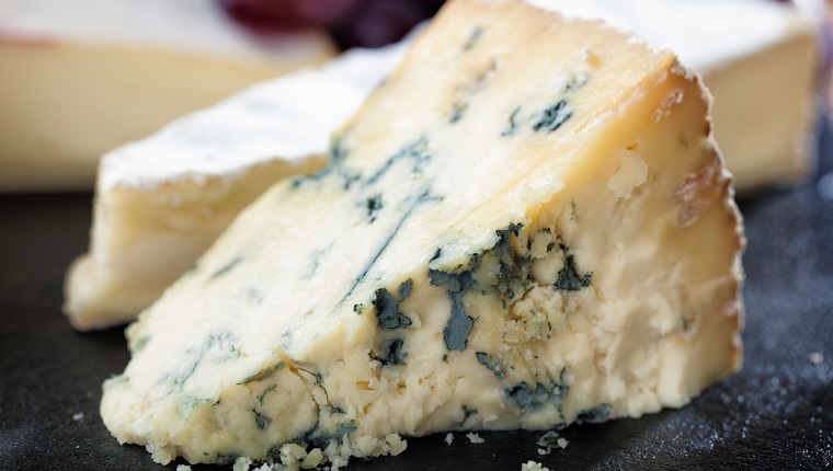 A selection of cheeses and grapes arranged on a slate cheese board.