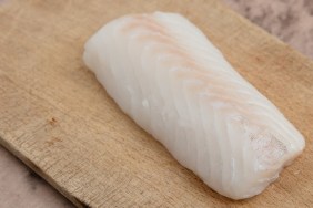 Codfish fillet on wooden board.