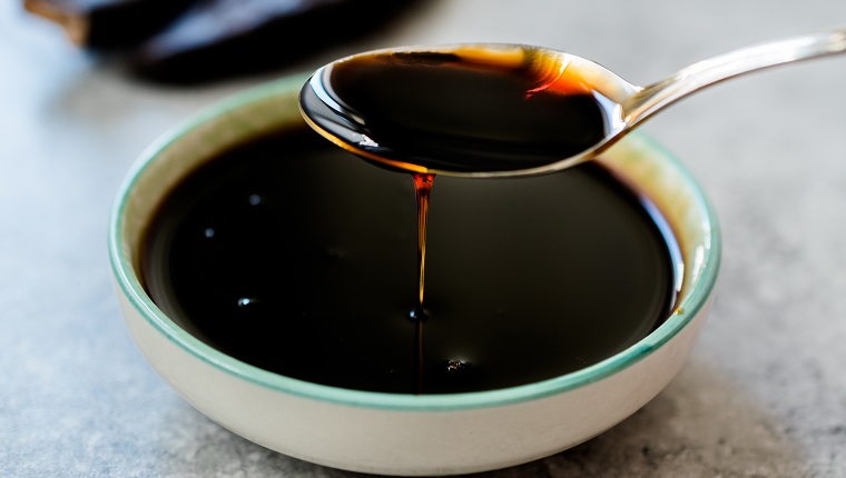 Carob Molasses Dripping from Spoon. Organic Food.