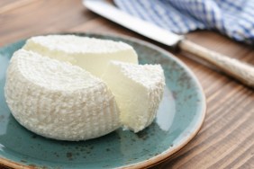 Fresh ricotta on plate on wooden background