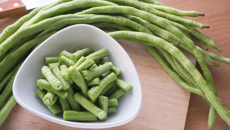 Sliced yard long bean vegetable on the white dish and wooden block, Asian's homegrown vegetable, View from top vegetable.