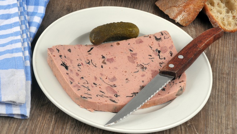 Slice of truffle liver pâté on a plate with a knife in close-up