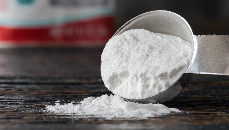 Close-Up Of Baking Soda Spilled From Measuring Spoon On Table