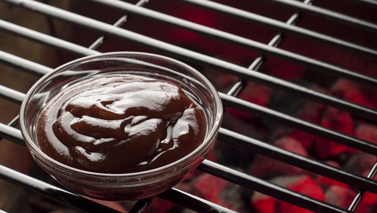 A bowl of BBQ sauce on the grill.