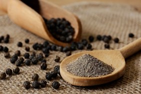 Ground Black Pepper and Peppercorns with wooden spoon and scoop. Studio shot on June, 18, 2018