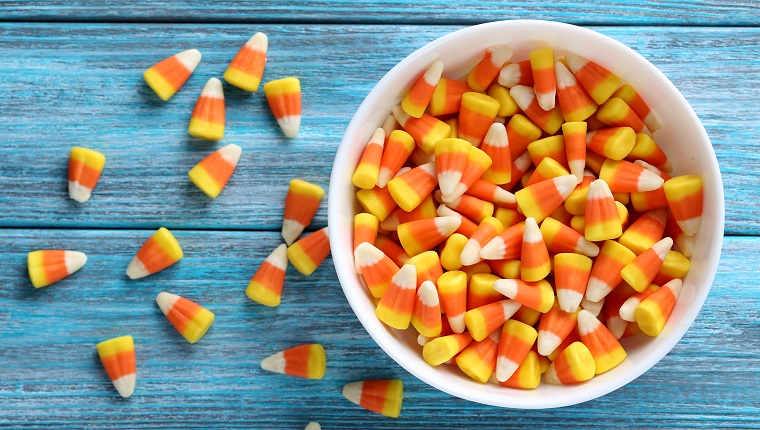 Halloween candy corns in bowl on blue wooden background