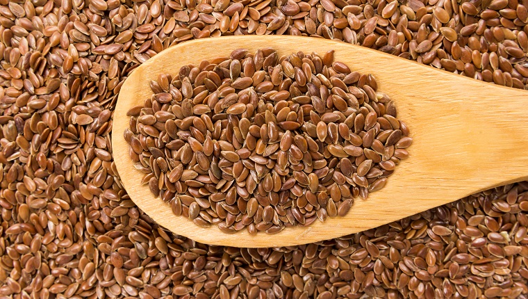 Linum usitatissimum is scientific name of Brown Flax seed. Also known as Linseed, Flaxseed and Common Flax. Grains in wooden spoon. Close up.