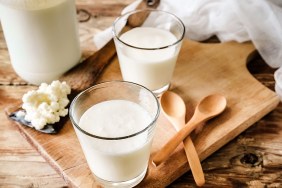 Organic probiotic milk kefir grains, Tibetan mushrooms, kefir grains in wooden spoon with glass of kefir. Rustic table setting, wooden table, spoon and cutting board.