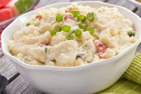 A delicious homemade creamy potato salad on a rustic picnic table.