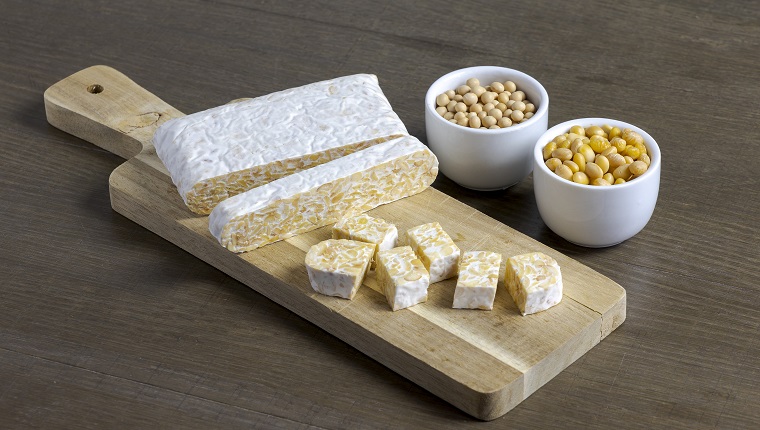 Indonesian, fermented soybeans cake, tempeh, for a plant based vegetarian diet on a wooden board