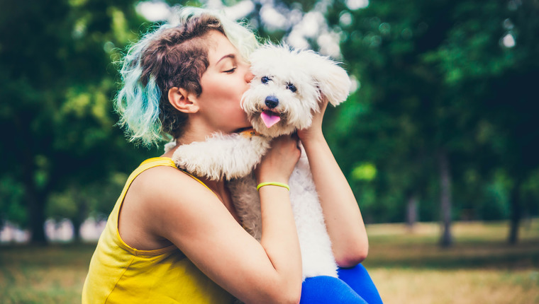 young dog owners kissing their dog in a park