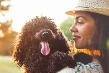 woman hugging poodle best dog breeds for a pisces