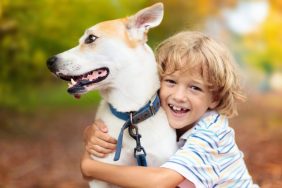 Smiling boy hugging small pit bull mix at their forever home.