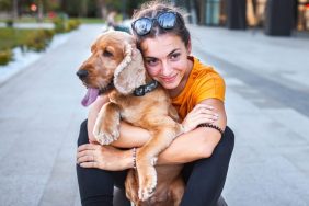 young woman hugging dog on bus stop bench