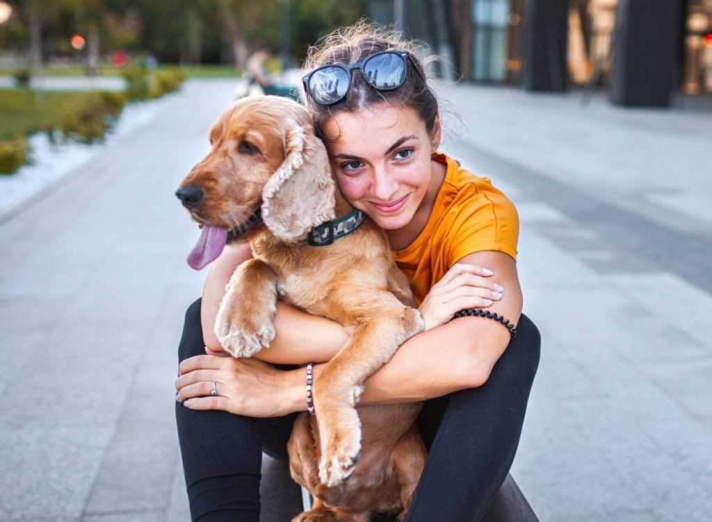 young woman hugging dog on bus stop bench