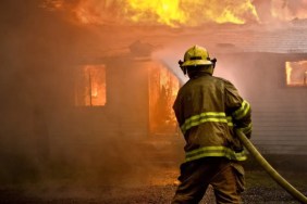 Firefighter spraying water at a house fire.