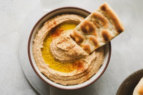 A closeup photo of pita bread and a bowl of hummus, which dogs should not eat due to seasonings containing garlic and onions.