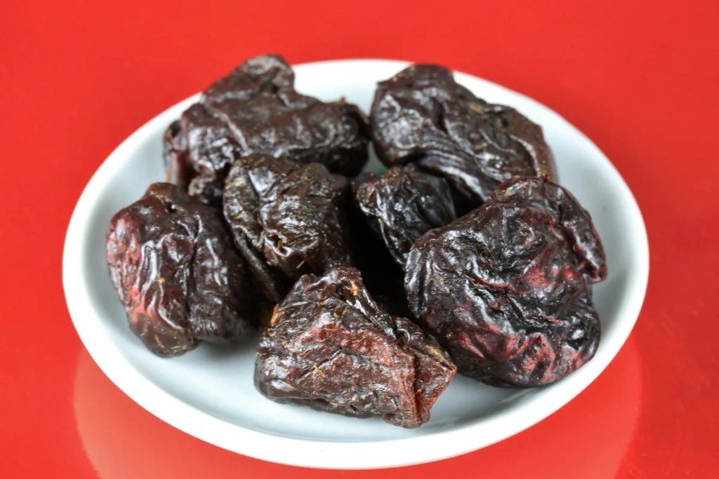 A plate of prunes, which dogs can eat but shouldn't due to their sugar content and pit which contains cyanide.